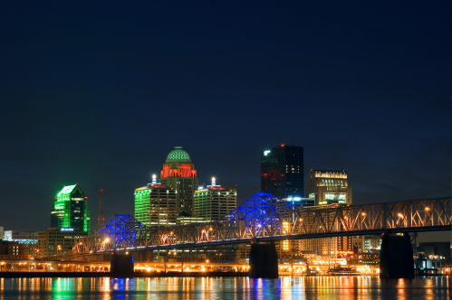 Louisville skyline at night with the Ohio River and a bridge.