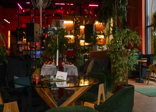 Upscale restaurant interior with candlelit tables surrounded by lush indoor plants.