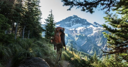 A backpacker hikes at the base of Mt. Hood in Oregon on a clear day.