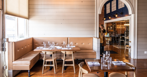 In a sun-drenched room, a tan leather booth sits empty, waiting for a busy night of diners.