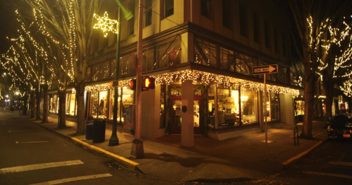 At night, a popular city street is decked out in holiday lights.