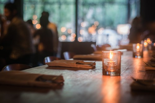 A candle sits before ready sits at a busy restaurant.