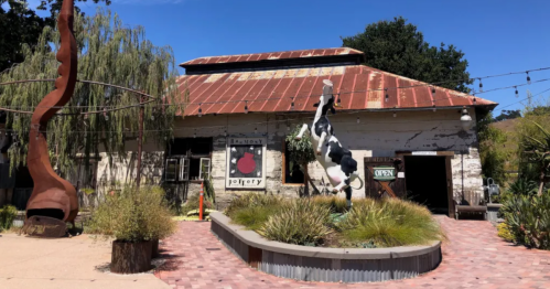 A cow statue stands in front of a unique building in Harmony, CA.
