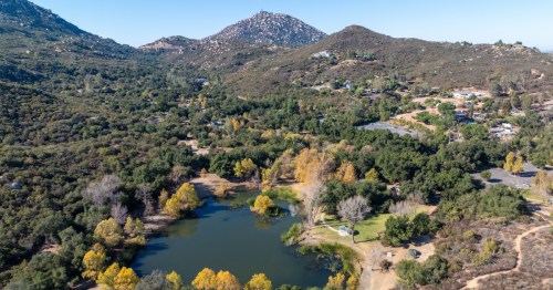 An aerial view of a Ramona, California, a small pond, and the surrounding mountains.
