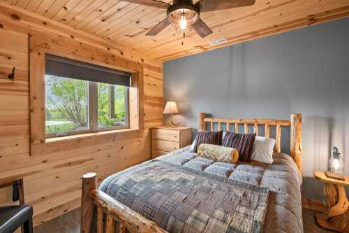 A cozy bedroom with natural wood and one spacious bed done up in cushy quilts and comforters.