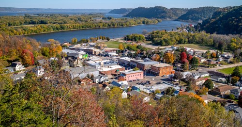 The downtown area of Lansing, Iowa, with its historic brick buildings and forested Mississippi River bluffs, photographed from an elevated position north of the town.