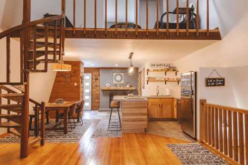 A white and natural wood-toned rustic space featuring a wooden spiral staircase leading to a loft.