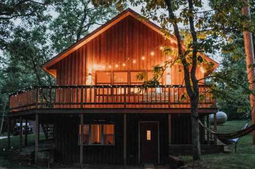 A cozy, forest-surrounded cabin with an elevated and well-lit deck.