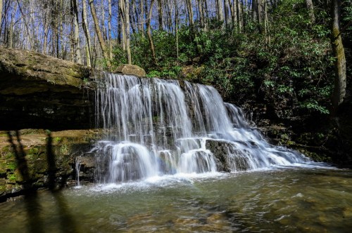 The cascading waters of Laurel Run Falls as it runs over the rocks like a curtain of flowing water into the blue pool below.
