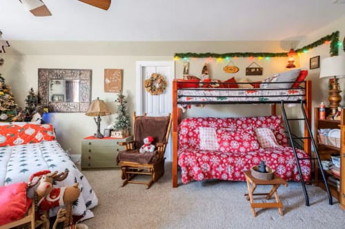 A spacious bedroom with a floor bed on one side and a bunk bed on the other. The room and the beds are adorned with gorgeous Christmas decorations.