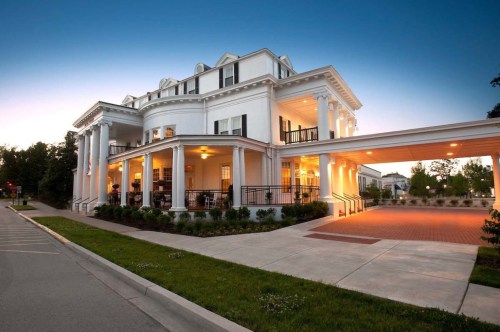 With large pillars, this white inn fits perfectly with many of the historic New York-style architecture and features beautiful black accents like railings.