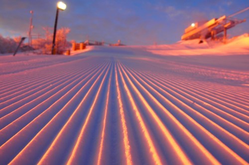 A perfectly groomed ski slopes during sunset.