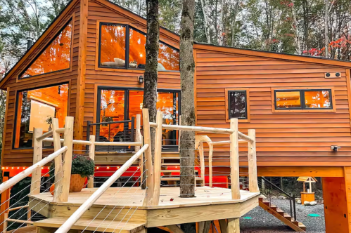 Exterior shot of the Secluded Luxury Treehouse airbnb in Newport, Vermont.The home is nestled among the trees and is lit up inside.