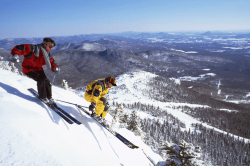 Two skiers at the top of a steep, snowy mountain at Jay Peak Resort in Jay, Vermont.
