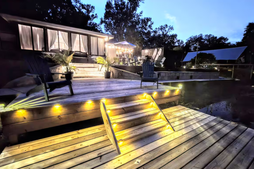 Exterior of cozy winter Airbnb in Florida at night, with a lit dock and deck.