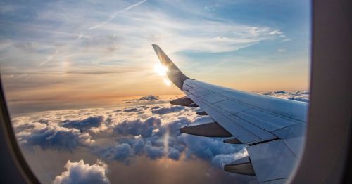 sunset image from the window of a plane with the plane's wing in the corner