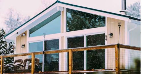 The exterior of a cabin in winter with a deck.