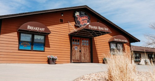 Front exterior of The Prairie Rose Inn in Kansas, featuring brown siding and "Breakfast" and "Bar & Grill" awnings.