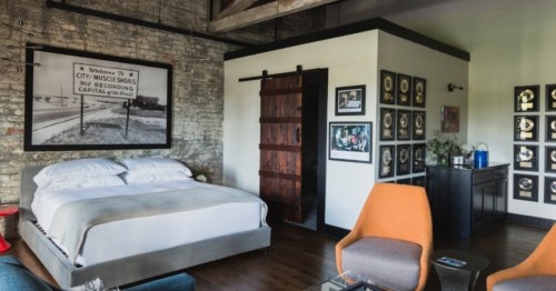 A room at the GunRunner Hotel and Bar in Alabama with modern accents and a bright orange chair.