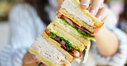 A woman holds a large club sandwich from No Name Deli in South Carolina.
