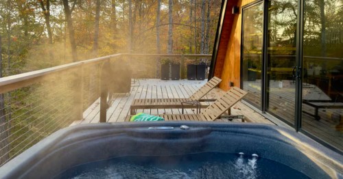 The deck view of a winter Airbnb in Kentucky with a hot tub and seating.