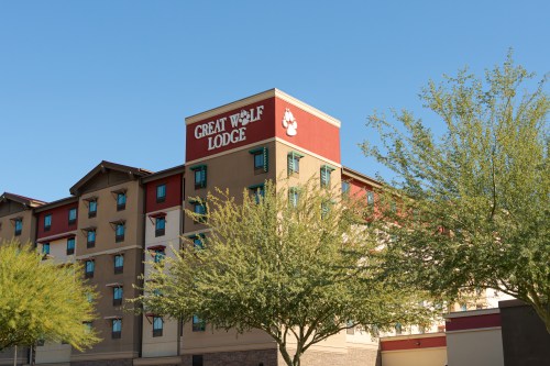 a tan and orange building with trees in front that says "great wolf lodge"