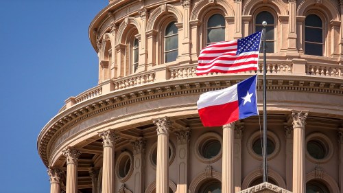 American and Texas state flags flying atop the dome of the Texas State Capitol building in Austin