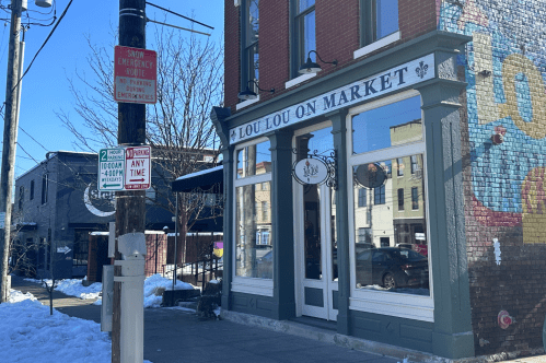 Exterior of Lou Lou on Market, with large windows outlined in green and a snowy sidewalk out front