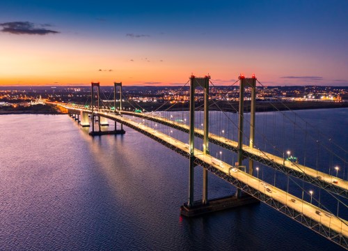 Twin suspension bridges glowing at dusk as they cross the Delaware River