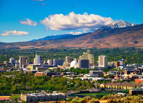 Downtown Reno, Nevada skyline featuring hotels and casinos, with surrounding mountains in the background.