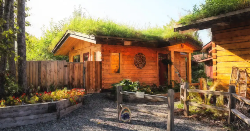 A beautiful wood building is surrounded by a lush garden and split-rail fence.