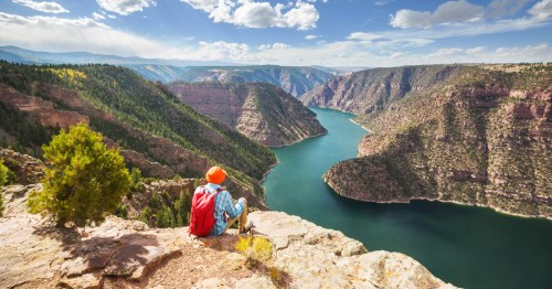 A hiker sitting and admiring the expansive views from a viewpoint over Flaming Gorge.