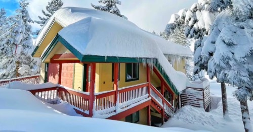 A yellow Airbnb near Lake Tahoe is covered in heavy snowfall.