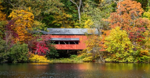 A red covered bridge in Ohio during fall.