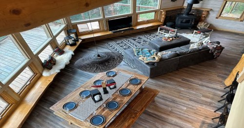 Living room and dining table in the middle of a winter cabin in Alaska nearby large windows.