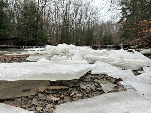 With a small waterfall in the distance, ice chunks sit beside a creek in Ohio.