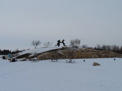 A man-made mound with a bronze statue towers over a snowy landscape in Dublin, Ohio.