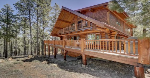 wooden cabin with a wraparound deck surrounded by trees in flagstaff, arizona