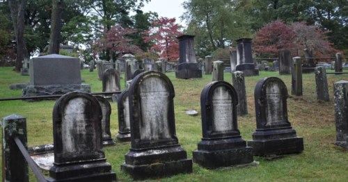 A large group of darkened gravestones in Sleepy Hollow Cemetery.