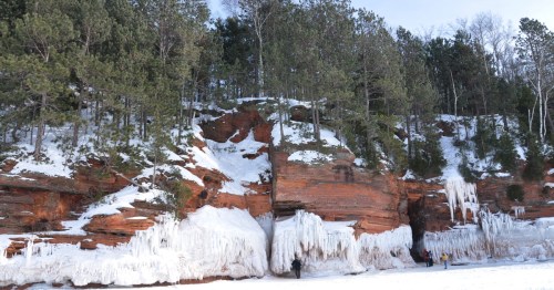 Massive ice formations and icicles cover the red cliff base, creating a stunning winter view of a Minnesota ice cave.