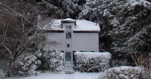 A snow-covered cottage surrounded by trees.
