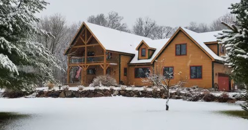 A rustic Iowa cabin stands peaceful and secluded, surrounded by a pristine, deep blanket of winter snow.