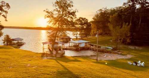 The backyard of a cabin in Louisiana overlooking the water at sunset.