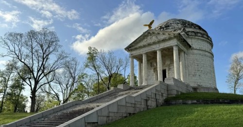 View of a large stone monument with stairs leading up to it on a partly sunny day.