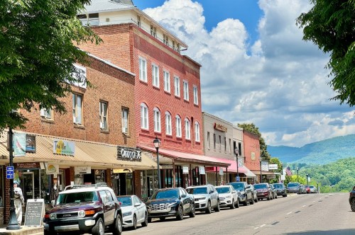 A Picturesque mountain downtown of Franklin North Carolina, with brick buildings and green peaks seen in the distance.