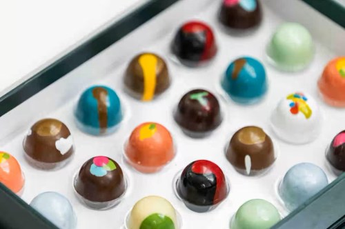 Colorful hand-painted chocolate bonbons in a box.