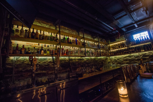 Hundreds of liquor bottle line the shelves of a bar at the Bramhall Restaurant in Portland, Maine. The lighting is very dim.