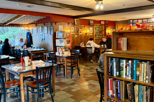The interior of the Traveler Restaurant in Union, Connecticut. Patrons dine at tables surrounded by shelves of books.