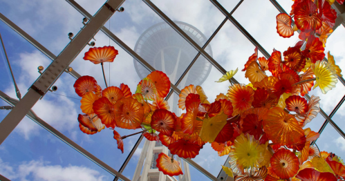 A delicate construction of glass stretches toward the ceiling with the Seattle Space Needle in the distance.