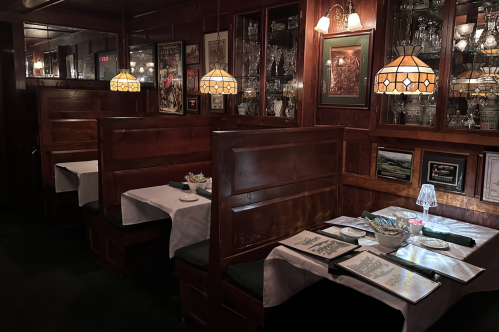 Pat's Steakhouse interior with booth tables, old-fashioned light fixtures, and wood-paneled walls.